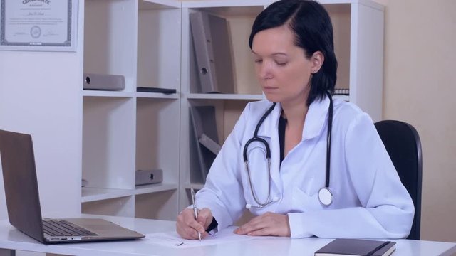 therapist works with medical records adult woman wearing white lab coat writing prescription side view