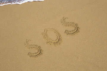 SOS,word drawn on the, sand beach with the soft wave