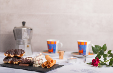 variety of biscuits on a table with coffee and flowers and candles