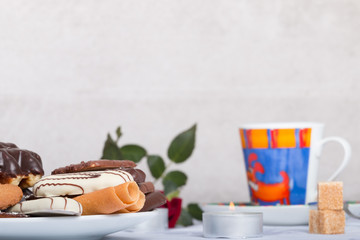 variety of biscuits on a table with coffee and flowers and candles
