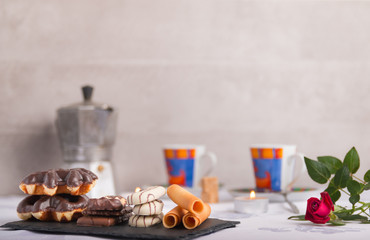 variety of biscuits on a table with coffee and flowers and candles