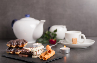 variety of biscuits on a table with coffee and flowers and candles