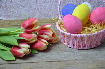 Obraz na płótnie Canvas Easter eggs and tulips bouquet on wooden background. Top view with space for your greetings