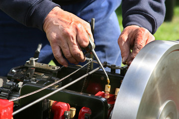Man oiling part on scale model steam powered traction engine.