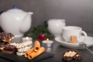 variety of biscuits on a table with coffee and flowers and candles