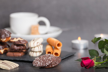 Obraz na płótnie Canvas variety of biscuits on a table with coffee and flowers and candles