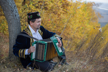 Мужчина татарин поет песню и играет на гармошке