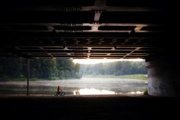 person on bicycle by the water under the bridge