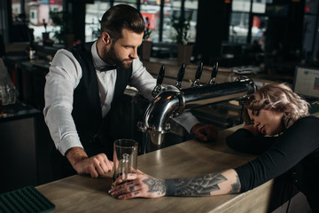 bartender looking at drunk girl sleeping at bar counter
