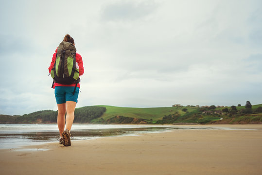 Backpacker girl traveler walk on deserted ocen beach