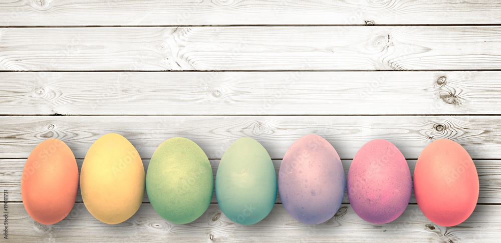 Wall mural Pastel colored eggs on  white wooden planks, panoramic easter background