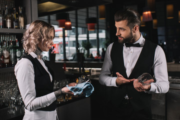 bartender showing at glass to colleague in bar
