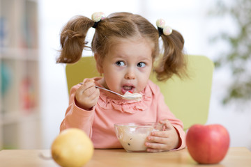 kid girl eating healthy food at home or kindergarten