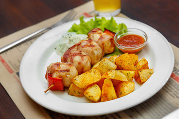 Meat barbecue from pork, beef with fried potatoes on a white plate. A hearty meal, dinner. Dish for the menu. Side view. Close up