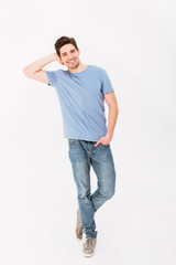 Full-length photo of caucasian attractive man in casual t-shirt and jeans smiling and posing on camera with hand in pocket, isolated over white background