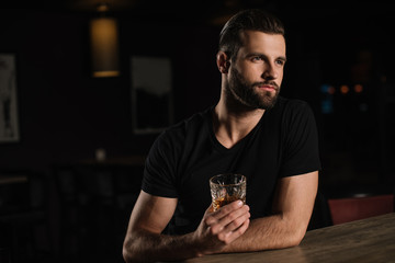 visitor sitting at bar counter and holding glass of alcohol drink