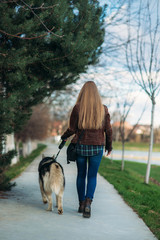 A girl is walking with a dog along the embankment. Beautiful husky dog