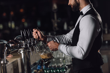 cropped image of bartender pouring beer from beer taps into glass