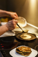 MAN COOKING PANCAKES ON COOKER RANGE