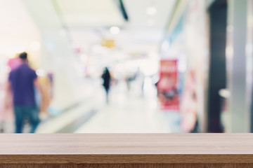 Empty wooden table top with blurred modern shopping mall background for product display and montage.