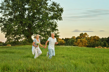 Naklejka na ściany i meble senior couple running in field