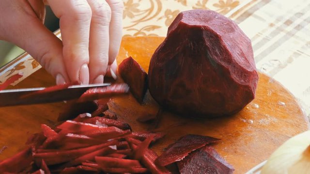Female hands cut beets on home kitchen board
