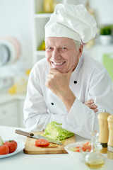 elderly male chef cooking salad