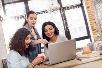 Great idea. Ambitious attractive three students looking at screen while working on laptop and wondering