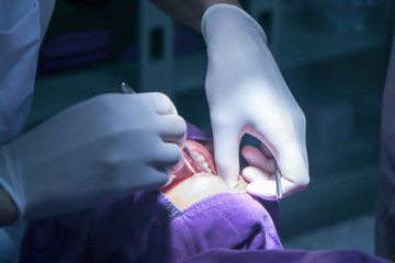 Dentist very carefully check up and repair tooth of his young female patient