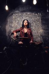 Fototapeta na wymiar brunette caucasian girl in red leather jacket with bicycle toned studio portrait