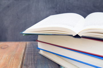 Opened books on a black chalkboard, wooden table