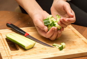 Slicing cucumber with a knife on the board