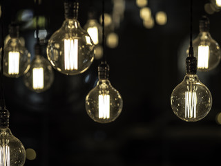 Filament vintage looking light bulbs or lamps hanging from ceiling against black background