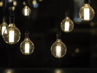 Filament vintage looking light bulbs hanging from ceiling against black background