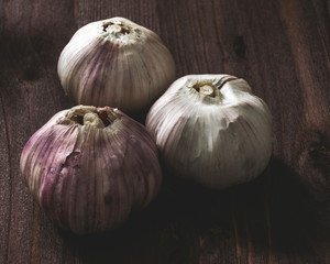 Obraz premium Three heads of garlic on wooden background