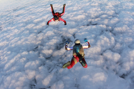 Two skydivers are in the winter sunset sky.