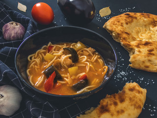 Traditional Uzbek dish is Lagman. Uzbek flatbread lavash, garlic, tomatoes, noodles, red pepper, eggplant, potatoes, onion. Delicious food. Black background