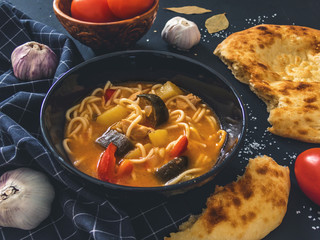 Traditional Uzbek dish is Lagman. Uzbek flatbread lavash, garlic, tomatoes, noodles, red pepper, eggplant, potatoes, onion. Delicious food. Black background