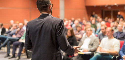 Speaker giving a talk on corporate Business Conference. Audience at the conference hall. Business...