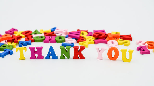The phrase "Thank you" built of wooden colored letters. Scattered in the background, colorful letters.