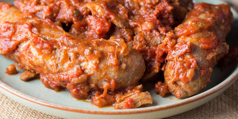 Sausages and pork pullet cooked in traditional Italian tomato ragu sauce. Dish on burlap. Banner
