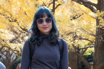 A trendy female traveller posing on the famous Genko Avenue with beautiful trees that have turned yellow in the autumn season in Meiji Jingu Gaien Park