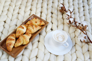 Cup with cappuccino and croissants, white pastel giant blanket, bedroom, flower cotton, spring, woman day, morning concept 