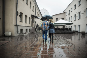 Fototapeta na wymiar happy loving couple is under an umbrella on a city street on a rainy day