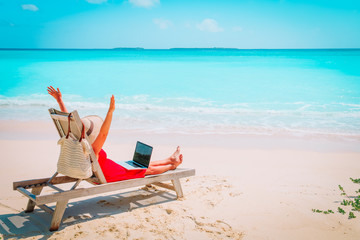 remote work concept -happy young woman with laptop on beach