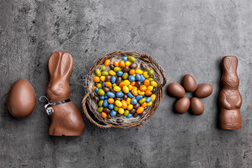 Chocolate Easter bunny, eggs and sweets on rustic background