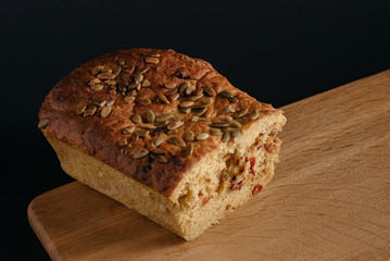 Pumpkin cake in a cut on a wooden plate on a black background