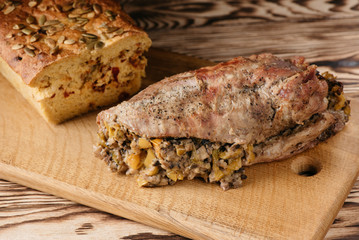 Pumpkin muffin and baked meat roll with a wooden stick on a black background