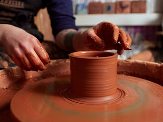 production process of pottery. Forming a clay mug on a potter's wheel.