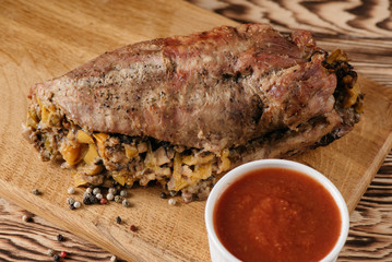 Pumpkin muffin and baked meat roll with filling along with a sauce on a wooden plate on a black background
